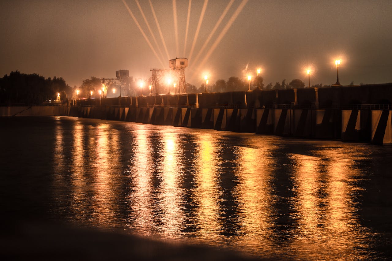 A scenic view of a brightly lit dam at night with reflections in the water.